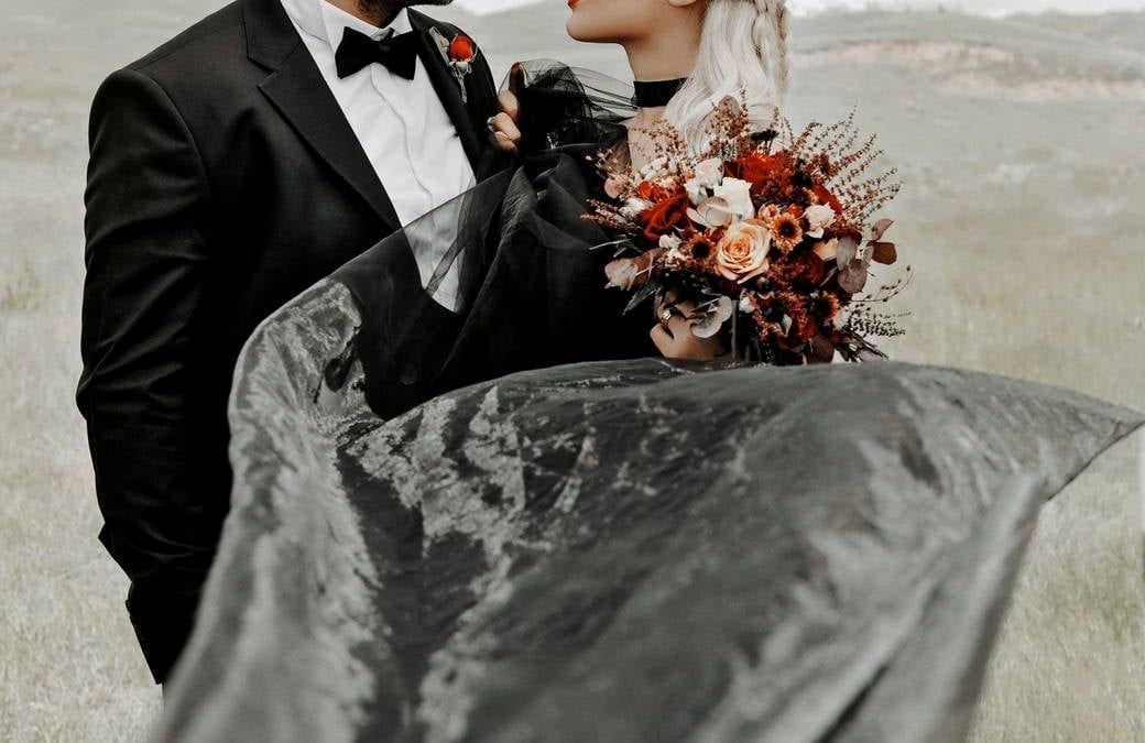 A couple in wedding outfits riding in a car